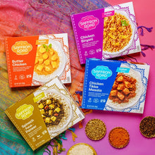 Load image into Gallery viewer, Butter Chicken Frozen Meal package, Chicken Biryani package, Chicken Tikka Masala package, Spinach Palak Paneer package on a bright Indian textile with spices 
